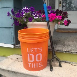 Photograph of orange trash bucket and trash picker on porch step.