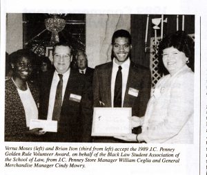 Black and white newspaper clipping of four people standing and smiling, to the left is a man presenting a check to a woman; to the right is a woman presenting an award to a man