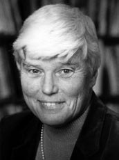 Black and white photograph of a woman with light hair, smiling at the camera