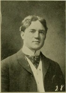 Black and white yearbook photograph of a man in a jacket.