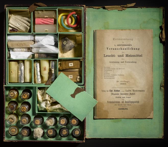 Photograph of an 19th century chemistry set, complete with chemical viles in compartments and a book with instructions on using it