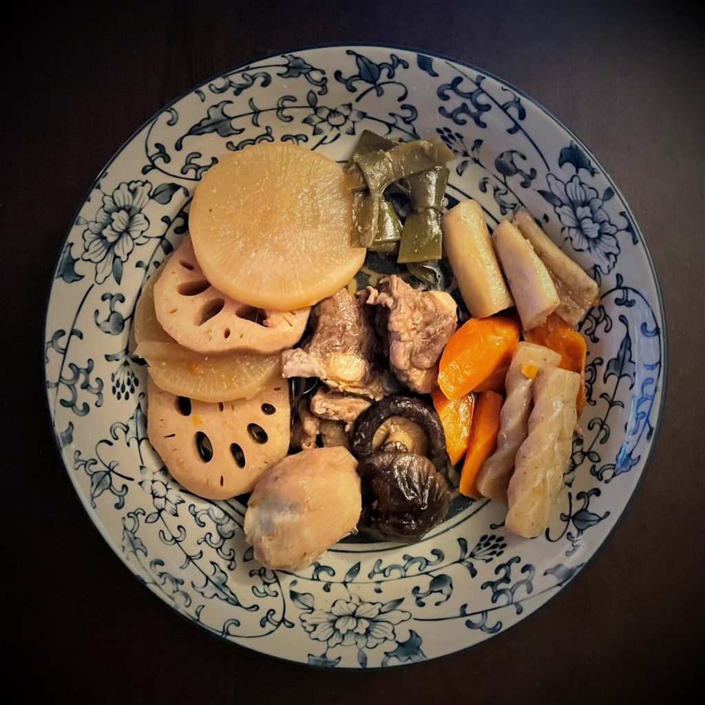 Blue and White floral plate with root vegitables, mushrooms, and kombu in a stew.