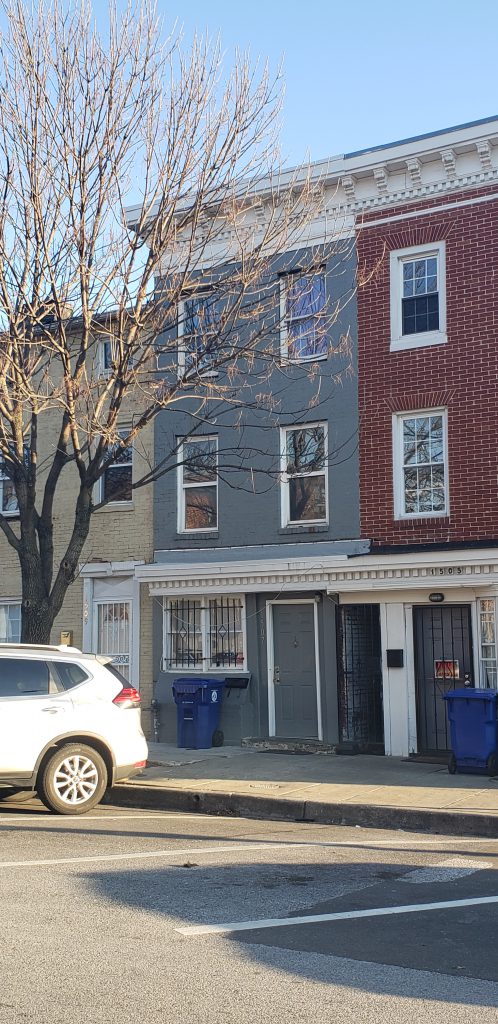 Photograph of three Baltimore City row homes, one is yellow, one is blue, and the third is red. 