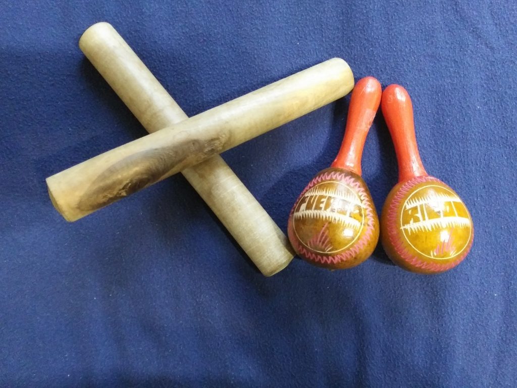 Photograph of two musical instruments, one set is long stick shaped criss-crossed to form an x, the second have long handles and bulb-like ends. 
