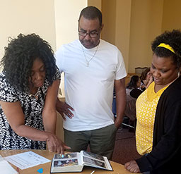 HS/HSL staff members Charlene Matthews, Patrick Williams and Shanell Stephens view old photos of the HS/HSL