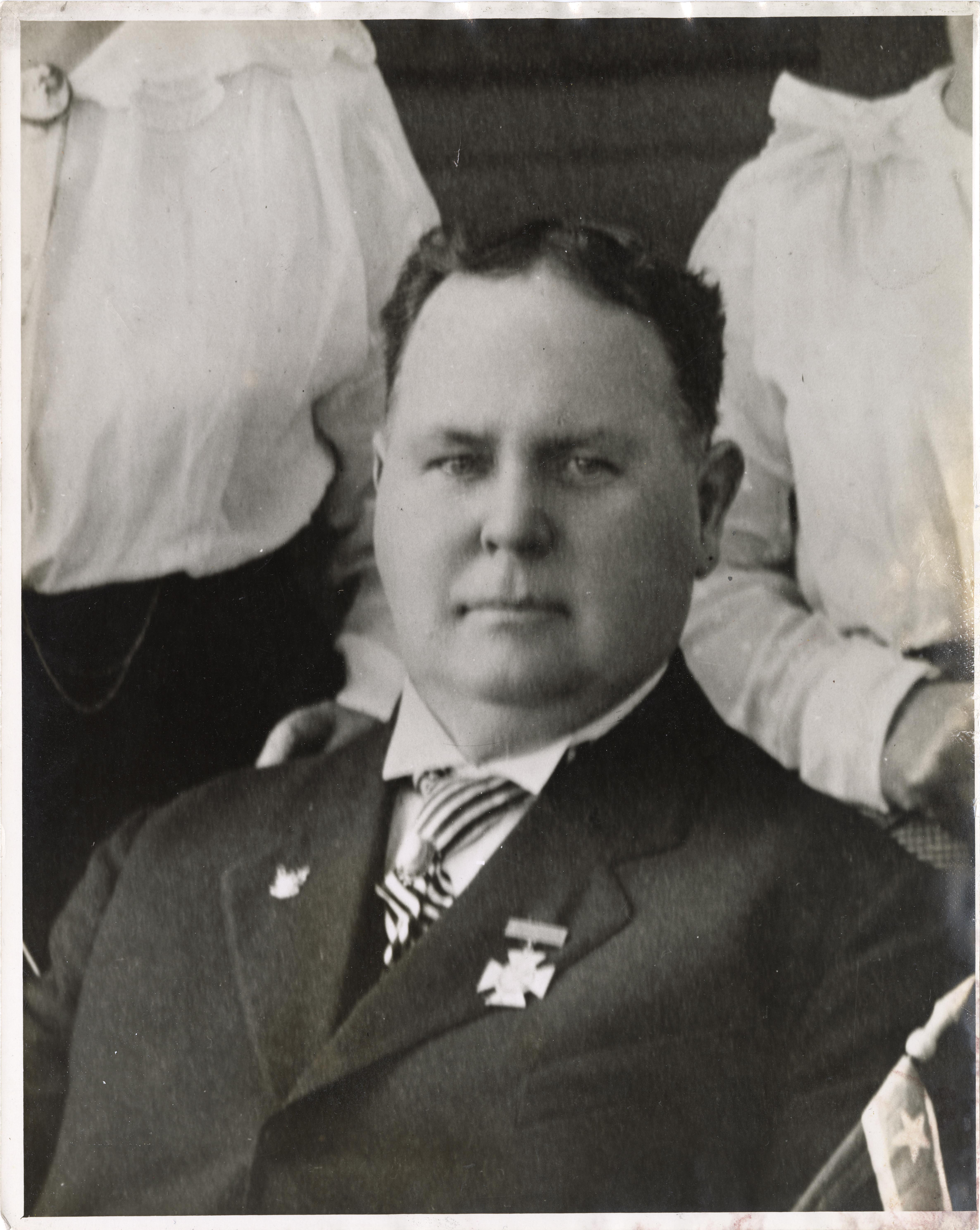 Black and white photograph of a man seated in a suit and tie.