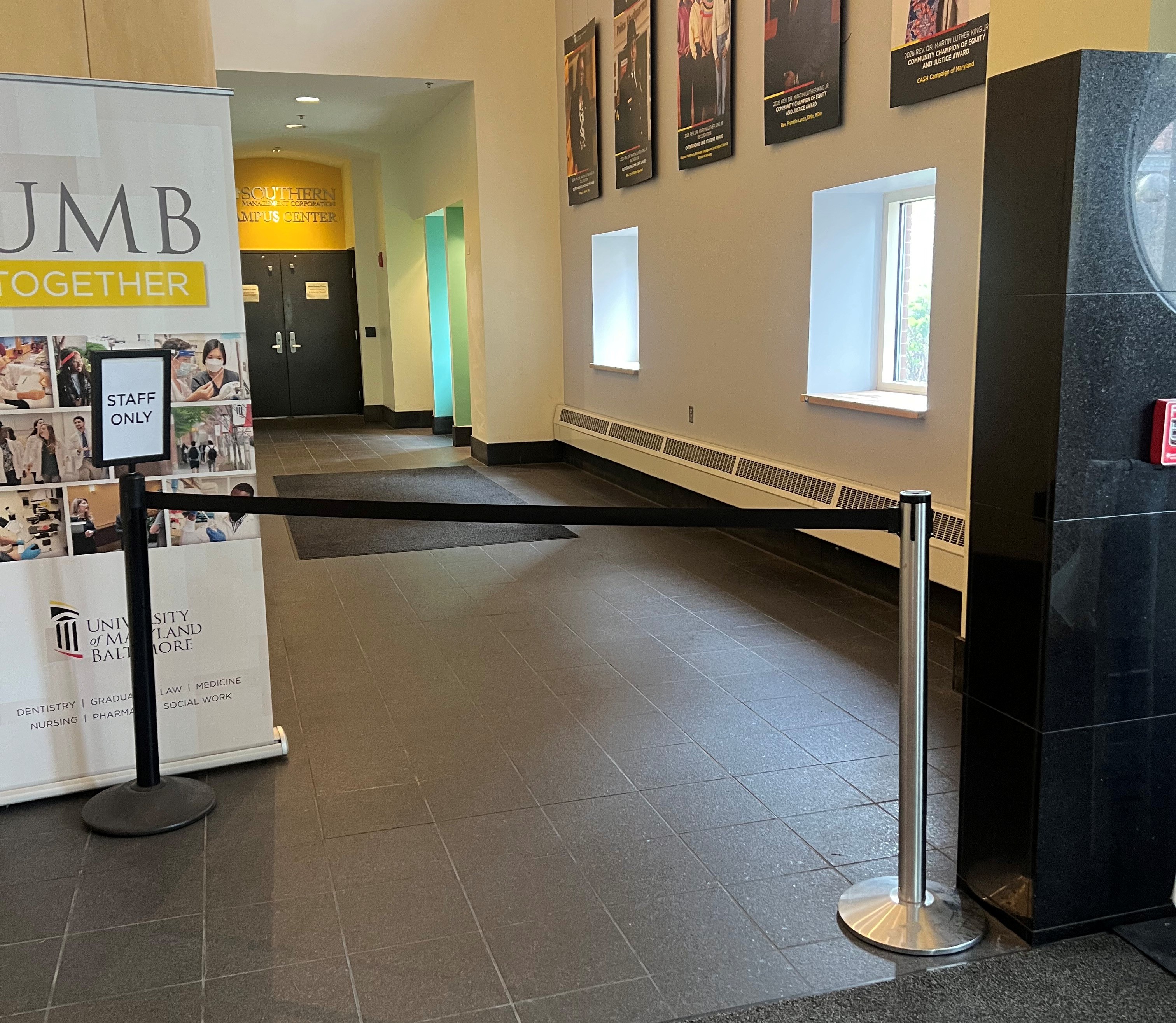 Indoor hallway with a black barrier labeled "Staff Only" and a University of Maryland, Baltimore banner.
